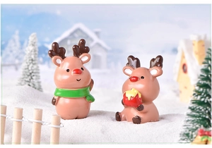 Macro view of two cute brown resin Christmas reindeer figurines in a snowy landscape