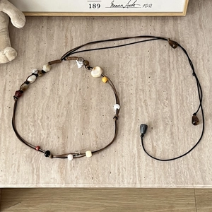 Detailed flat lay of bohemian braided waist chain with ceramic and wooden beads