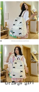 Detail of white corduroy backpack with black ribbon criss-cross and spacious side pockets
