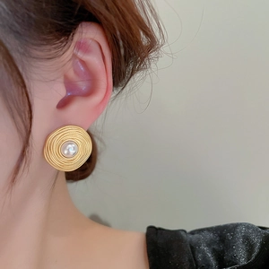 French vintage gold spiral stud earrings with center white pearl on a model's ear