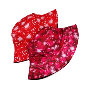 Detail of red bucket hats featuring romantic heart patterns and LOVE typography prints