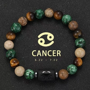 Detailed top view of Cancer zodiac bracelet with tiger eye beads and agate on black sand
