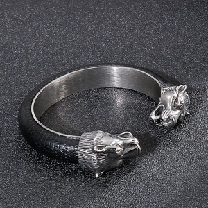 Macro shot of silver twin lion heads on a black textured leather open cuff bracelet