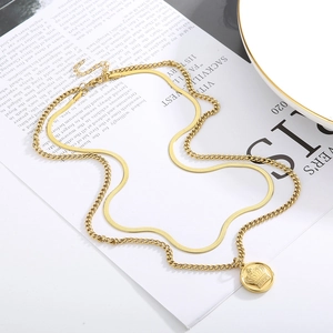 Detail of 18k gold-plated crown pendant and snake chain on newspaper background