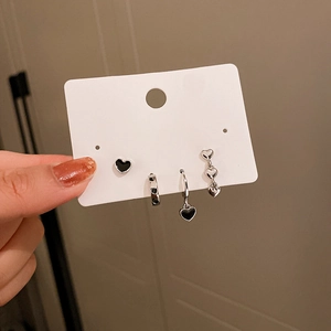 Detail of silver heart earring set including black enamel studs and dangles on a card