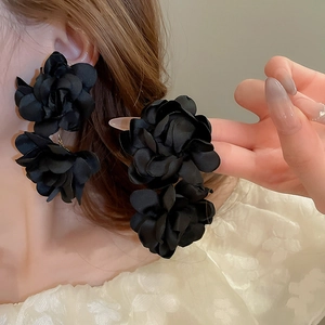 Vue détaillée de grandes boucles d'oreilles fleurs en satin noir portées par un mannequin