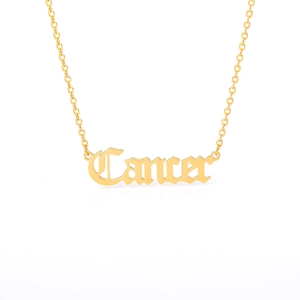 Detail of a golden Cancer zodiac pendant necklace with polished cutout lettering