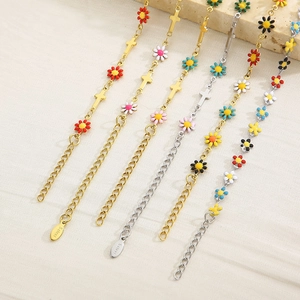 Detail of stainless steel daisy and cross charms on gold and silver chain bracelets