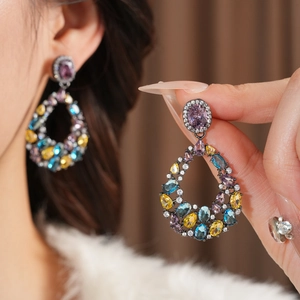 Dettaglio di orecchini vintage a goccia con cristalli di zircone viola, gialli e blu