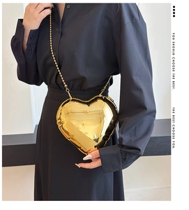 Detailed close-up of a glossy gold heart-shaped crossbody bag with a beaded chain strap