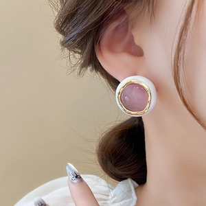 Detail of round cat eye opal stud earring in gold plating on female earlobe