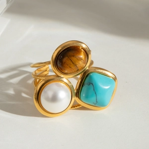 Vintage gold triple-stone ring with pearl, turquoise, and tiger eye on a multi-layer band