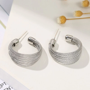 Detailed close-up of silver textured multi-layered hoop earrings on a minimalist background