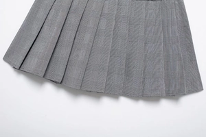 Gros plan sur la jupe-culotte plissée à carreaux gris montrant la texture du tissu fin