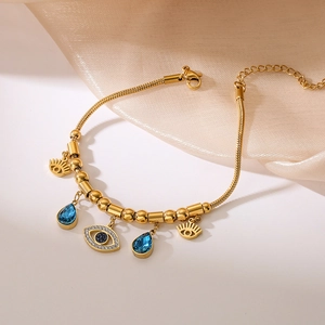 Gold evil eye bracelet with blue zircon pendants on silk fabric background