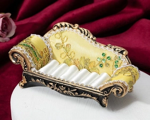 Detailed macro view of yellow vintage sofa-style jewelry display stand with lace