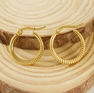 Detailed close-up of 18K gold-plated hoop earrings with textured vertical stripes on wood