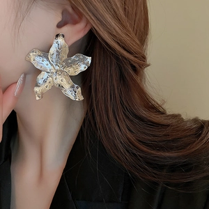 Close-up of oversized silver flower earrings with hammered metal texture on female model