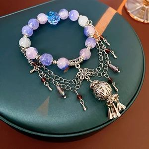 Detail of beaded flower bracelet with purple crystal gems and silver tassel pendants