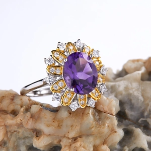Macro shot of oval purple gemstone ring with diamond halo on two-tone floral band