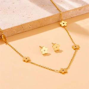 Golden flower jewelry set with hollow petal necklace and stud earrings on a stone base