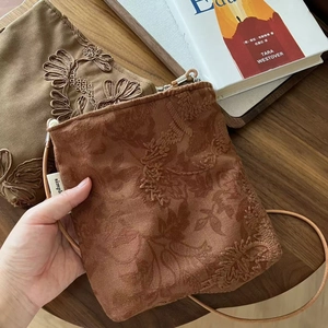 Gros plan détaillé de la broderie florale vintage sur sacs bandoulière en daim camel