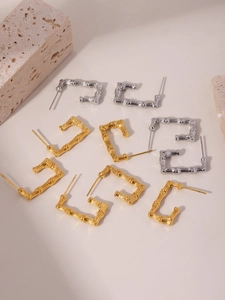 Macro view of bamboo texture U-shaped rectangle earrings in gold and silver steel finish