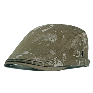 Close-up of distressed olive green flat cap with vintage textured splatter pattern and side buckle