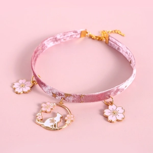 Detailed view of pink velvet pet collar featuring gold cherry blossom and cat pendants