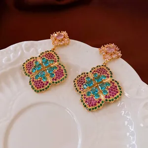 Vintage floral drop earrings with pink center stone and colorful crystals on white porcelain