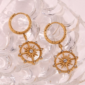 Détail macro de boucles d'oreilles boussole étoilée avec cristaux sur surface en verre