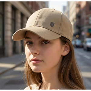 Detailed side view of khaki baseball cap with a metal shield badge and parallel stitching