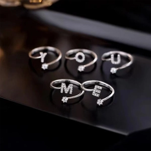 Detailansicht von fünf silbernen Ringen mit glitzernden Buchstaben und Zirkon-Sternen