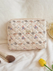 Quilted elephant pattern makeup bag with gold logo and floral decor on soft fabric