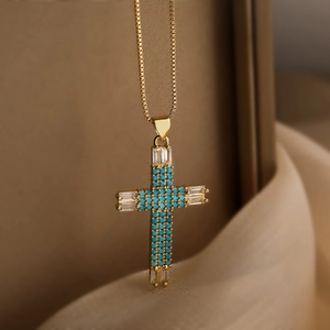 Elegant gold cross necklace with light blue zircons and pearls on silk fabric