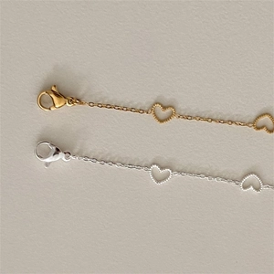 Macro detail of silver and gold heart link bracelets with delicate beaded textures