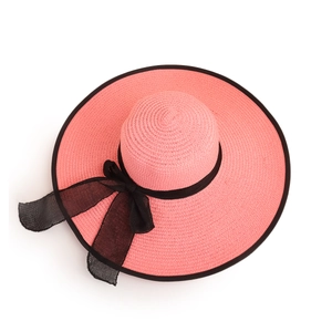 Detailed view of the woven texture and black ribbon bow on pink straw sun hat