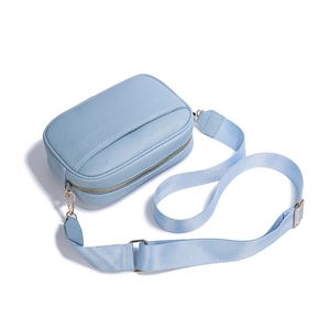 Light blue faux leather crossbody camera bag with adjustable wide fabric strap on white background