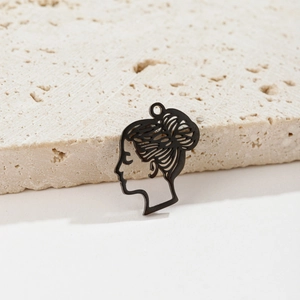 Macro view of black irregular abstract line face pendant on a beige textured stone