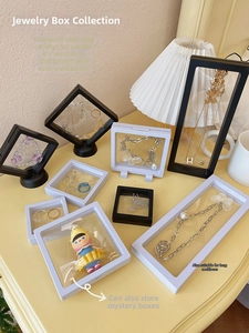 Black and white PE film floating jewelry boxes for rings and necklaces on a desk
