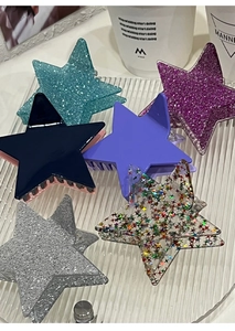 Close-up of star-shaped hair claws with colorful glitter finish and spring clip mechanism