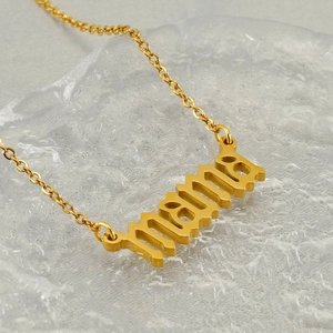 Golden MAMA pendant necklace in stainless steel displayed on a crystal ice background