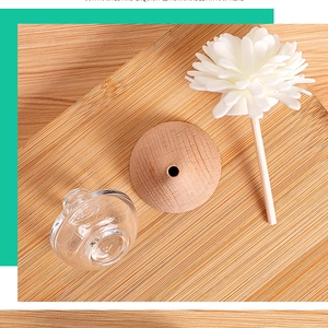 Top view of glass diffuser bottle with wooden lid and fiber flower on wood board