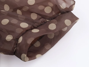 Detail shot of brown organza fabric with beige polka dots and pleated cuff design on dress
