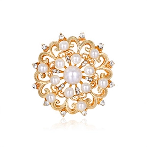 Close-up of vintage golden filigree brooch with a central pearl and crystals