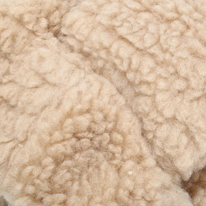 Macro view of thick beige Sherpa fleece material showing dense curly wool texture