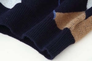 Macro detail of ribbed cuff on navy blue argyle knit sweater with high precision stitching