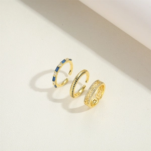 Detailed view of three vintage gold adjustable rings with blue and clear gemstones