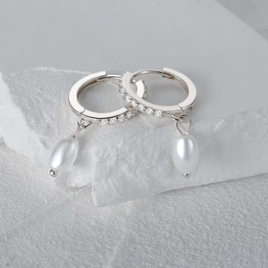 Detail of silver pearl drop earrings with sparkling cubic zirconia on a marble base