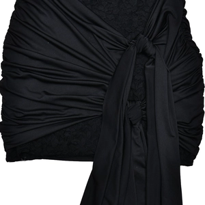 Detail view of black bodycon dress featuring pleated ruffles, bow tie, and lace trim